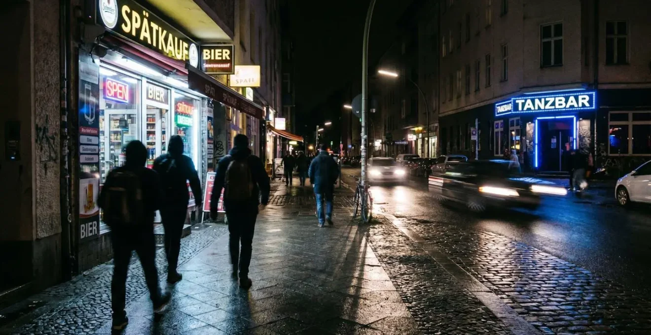 Rue berlinoise animée à 3 heures du matin avec Späti éclairé et entrée de club, personnes en mouvement flou symbolisant le rythme nocturne incessant de la ville.